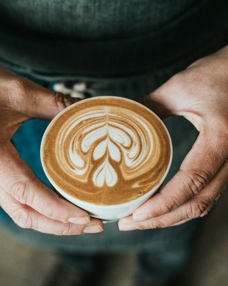 Хоёр гараараа барьсан latte art-тай аяга