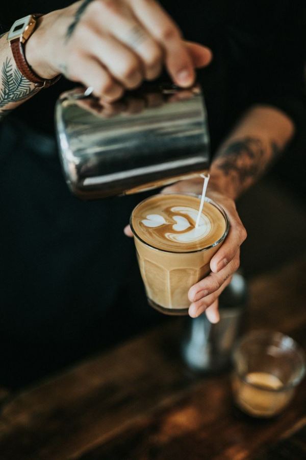 Бариста шилэн аяганд latte art цутгаж байна